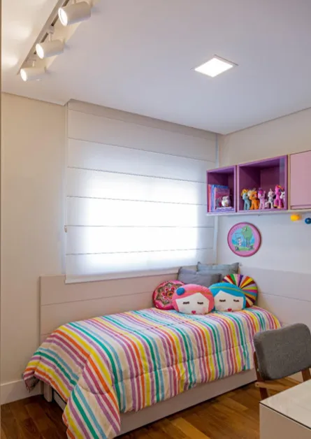Quarto infantil com colcha listrada colorida, nichos rosa e roxo com bonecas e persiana blackout, antes da reforma
