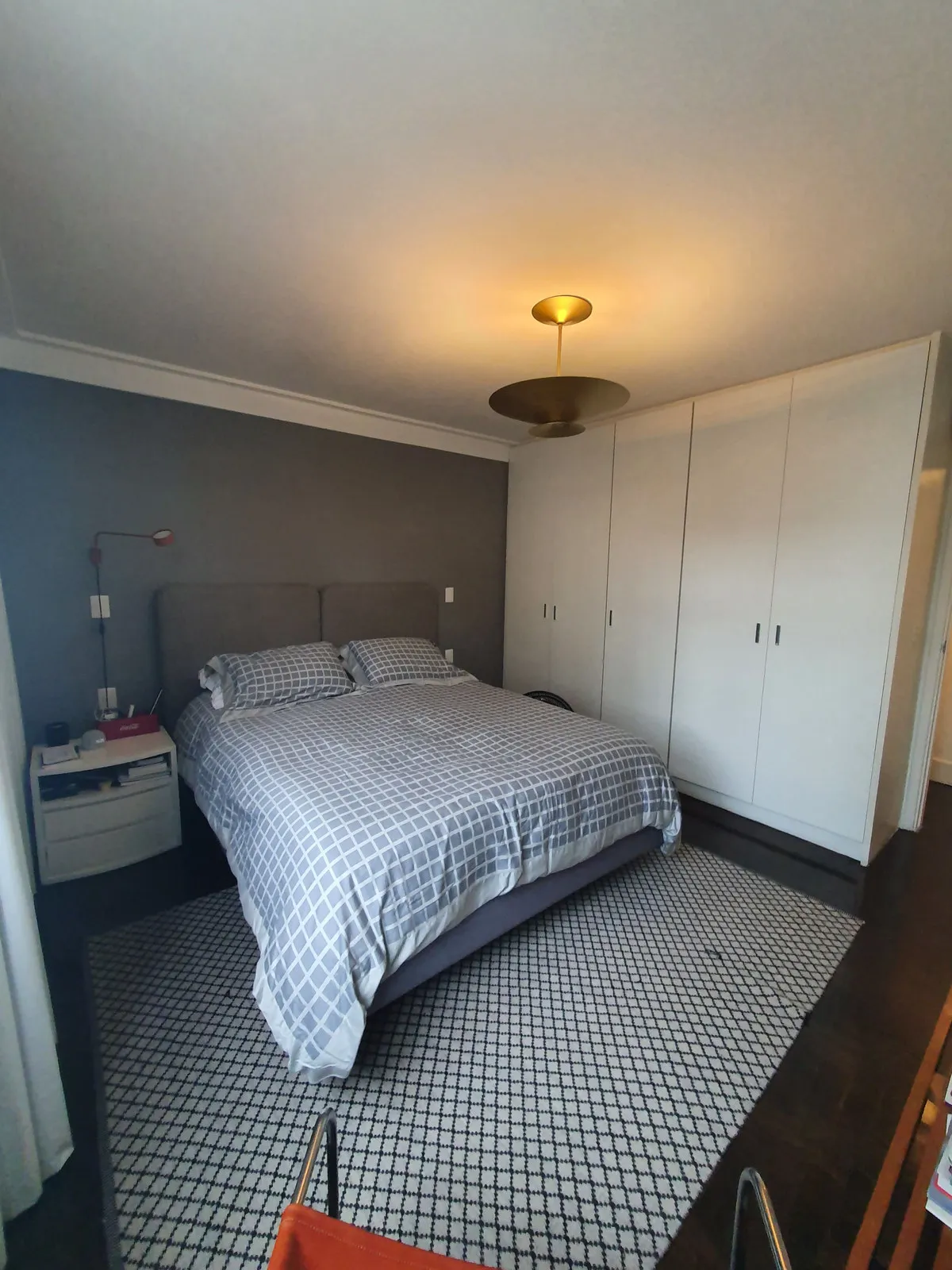 Quarto de casal com guarda-roupa branco embutido, parede cinza e criado-mudo, antes da reforma