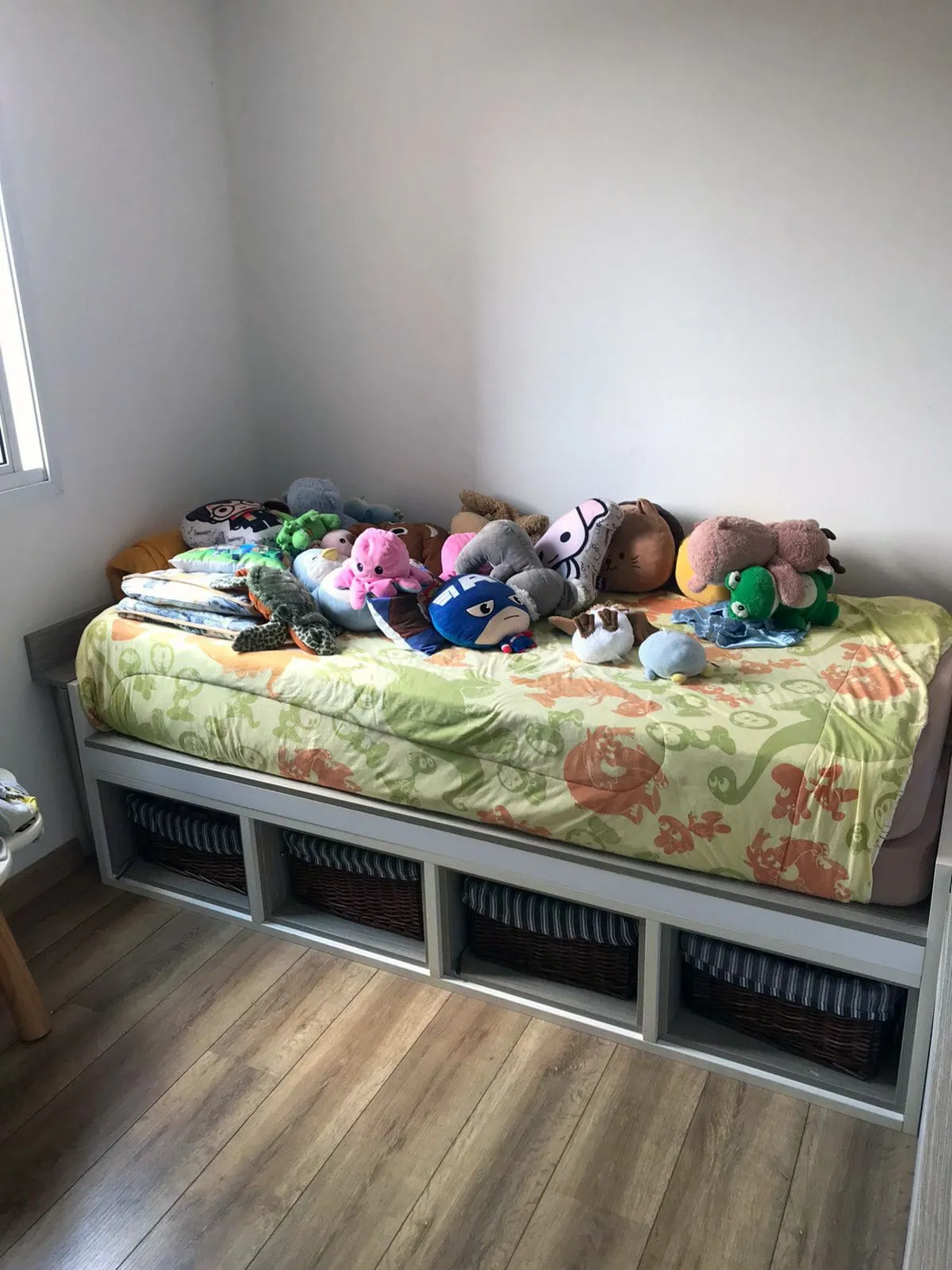 Quarto infantil com cama de solteiro, nichos com cestos, pelúcias e piso de madeira, antes da reforma