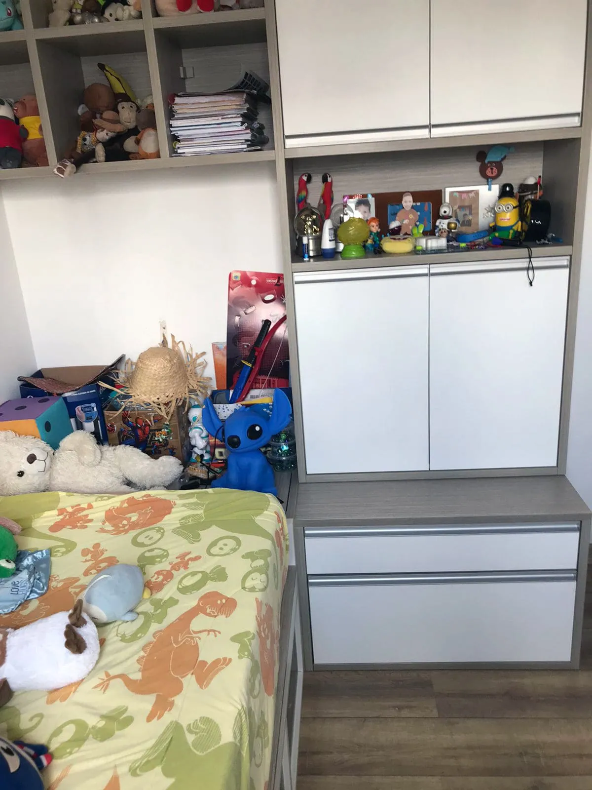 Quarto de criança com marcenaria cinza, gaveteiro, brinquedos espalhados e cama infantil, antes da reforma