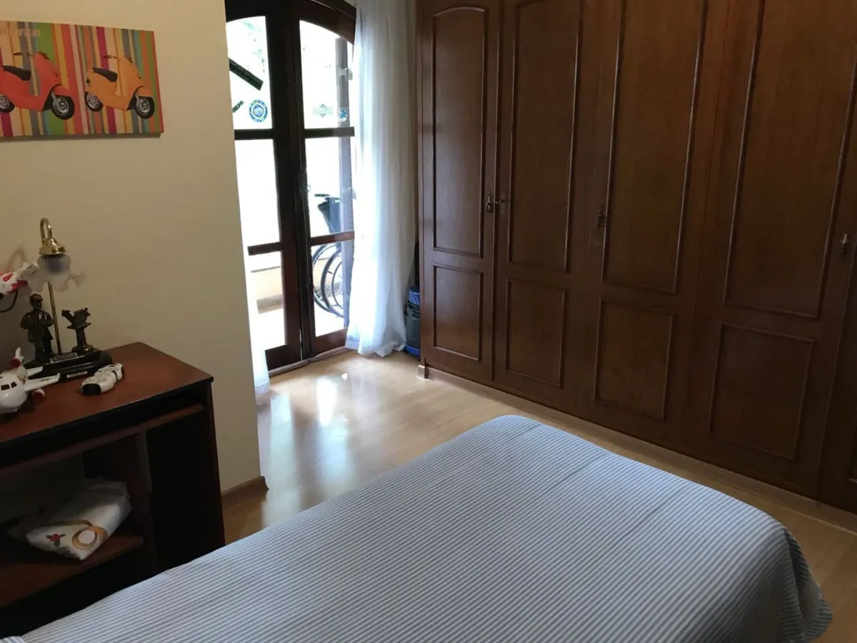 Quarto com guarda-roupa de madeira maciça escura, cama listrada e porta francesa para a sacada, antes da reforma