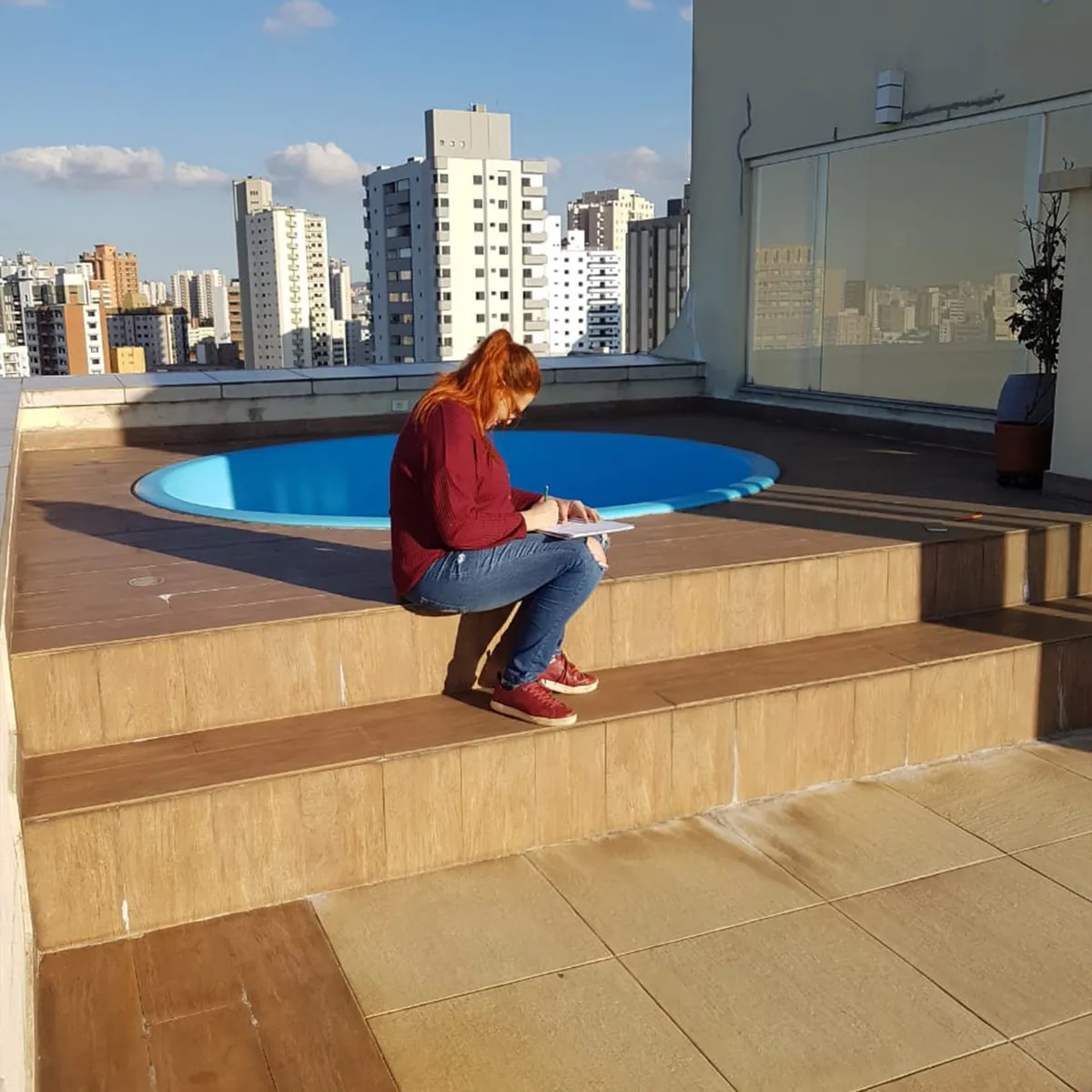 Terraço da cobertura com piscina redonda azul e vista dos prédios da cidade, antes da reforma