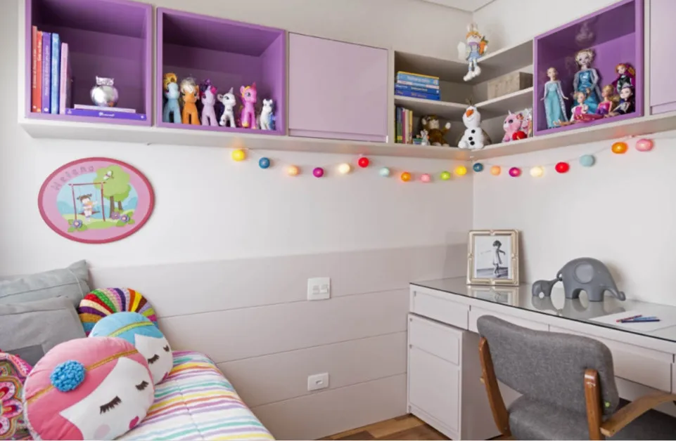 Canto do quarto com nichos lilás cheios de bonecas e cavalinhos, luzes coloridas e cama com almofadas de unicórnio, antes da reforma