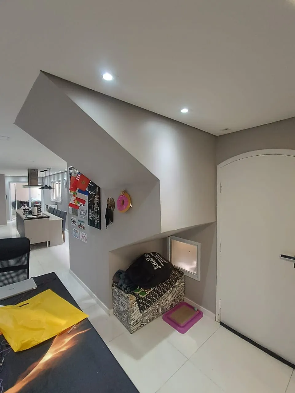 Hall de entrada com porta arqueada e nicho embaixo da escada, piso branco, antes da reforma