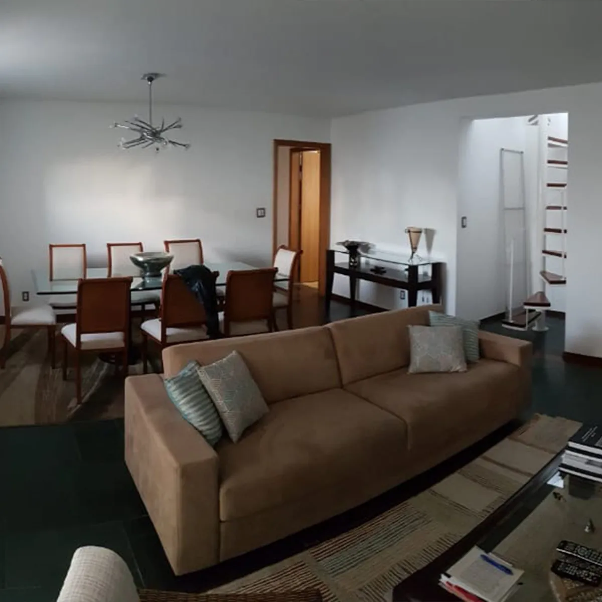 Sala de estar e jantar com sofá marrom, cadeiras de madeira e piso de pedra verde escura, antes da reforma
