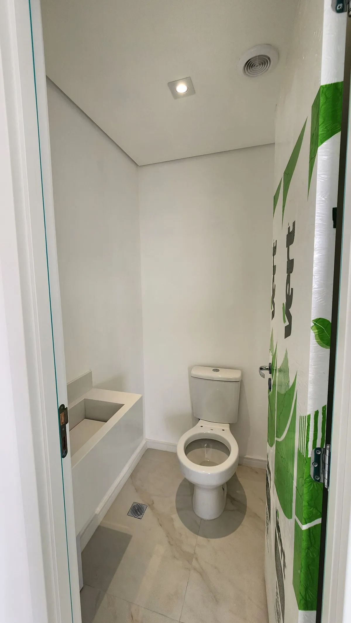 Lavabo estreito com vaso sanitário e bancada de pedra clara ainda sem cuba, antes da reforma