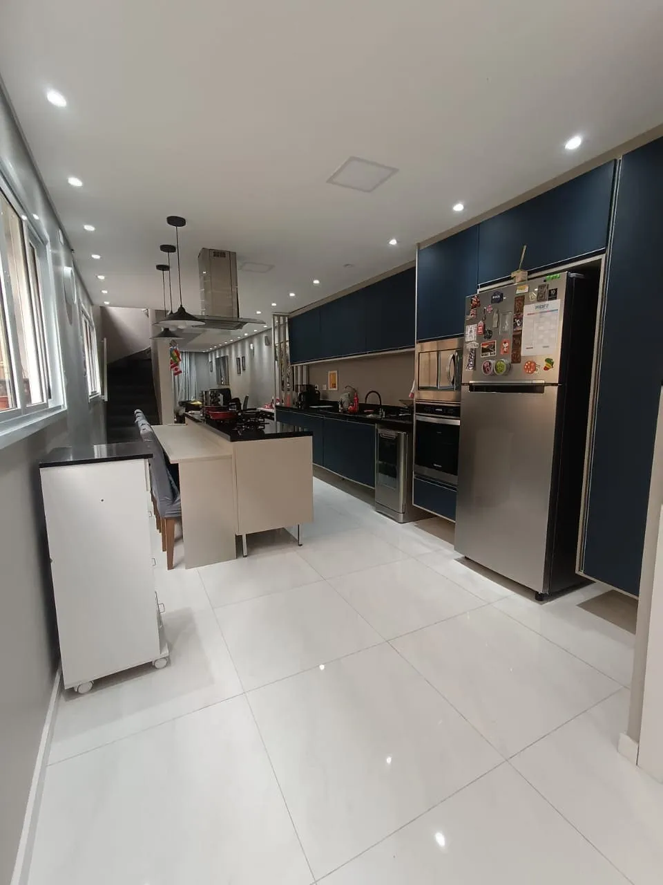 Cozinha com armários azuis, geladeira inox e ilha com cooktop, antes da reforma