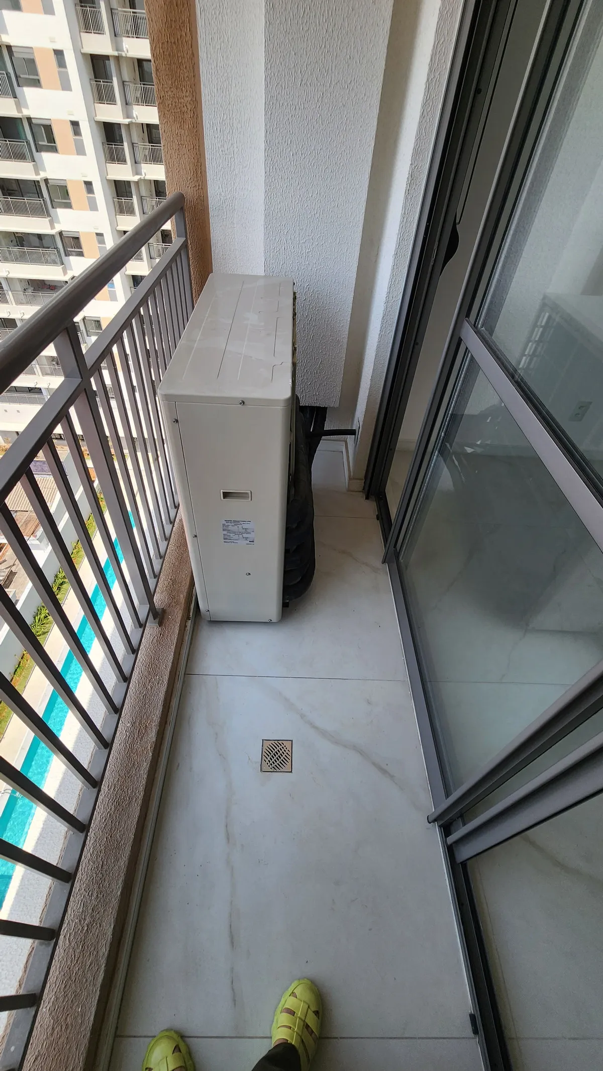 Sacada estreita com condensadora de ar-condicionado e aquecedor a gás, vista da piscina do prédio, antes da reforma