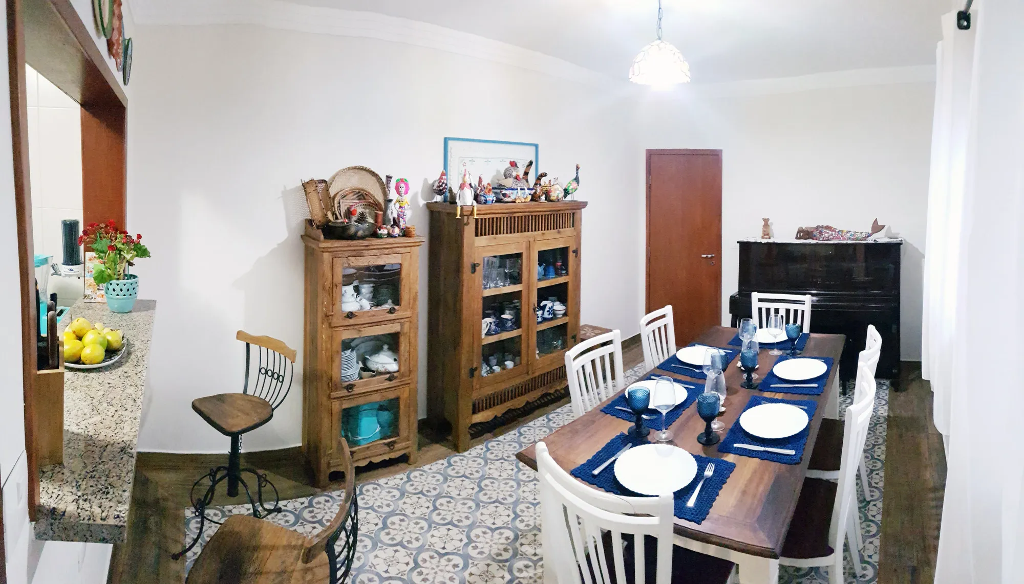 Sala de jantar rústica com mesa de madeira posta e buffet com coleção de objetos