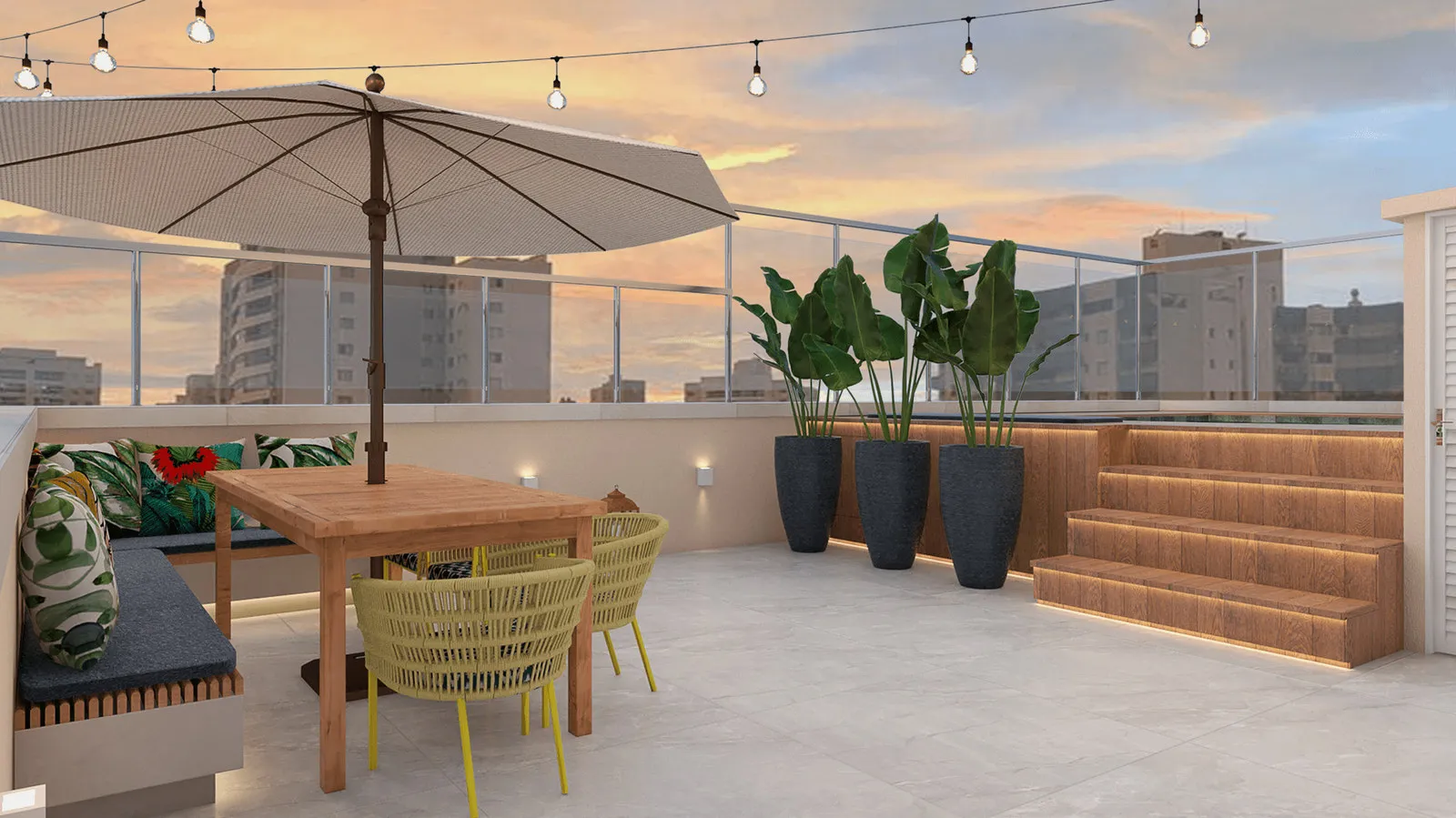 Terraço na cobertura com mesa de madeira, guarda-sol, banco com almofadas tropicais e vista da cidade ao entardecer
