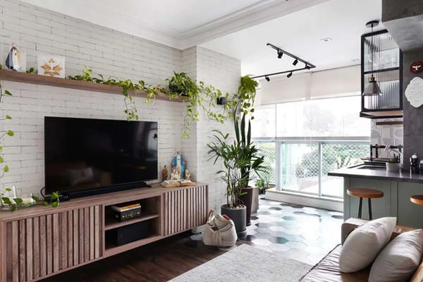 Living com parede de tijolo branco, marcenaria ripada e luz de trilho, apartamento em São Bernardo